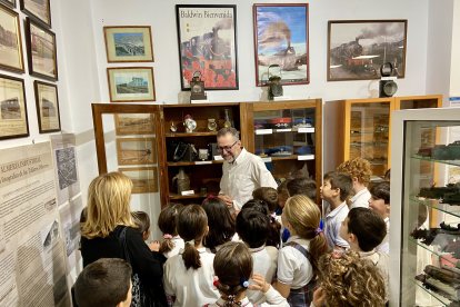 El guía explica al grupo visitante el funcionamiento de un teléfono antiguo portátil.