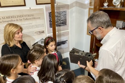 El guía explica al grupo visitante el funcionamiento de un teléfono antiguo portátil.