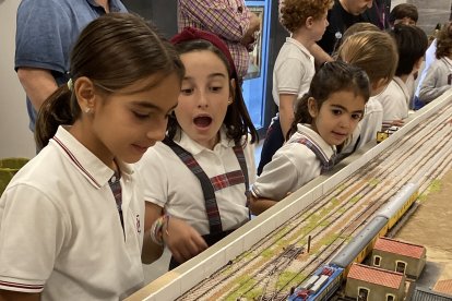 Alumnas contemplan asombrados la salida de los trenes de la pequeña estación recreada en la maqueta.