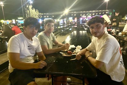 Ángel, Adrián e Isaac, amigos de Almería, prueban la comida del evento mientras disfrutan de una animada charla.