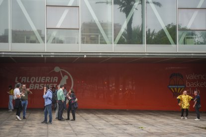 Varias personas llevan cajas con mantas, ropas y objetos de primera necesidad para las personas que se encuentran en el pabellón de baloncesto.