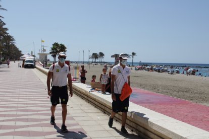 Auxiliares de playa informando de la obligatoriedad de usar la mascarilla.