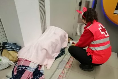 Voluntaria de la Cruz Roja llevando alimentos a una persona que se encuentra en situación de calle.
