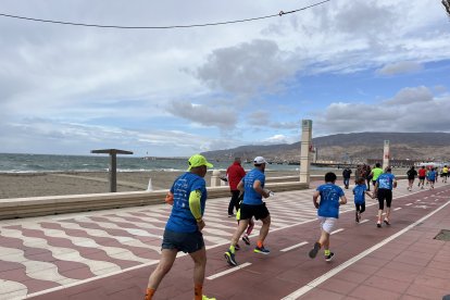 Corredores en fila por el paseo marítimo.