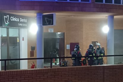 Bomberos junto al portal del edificio en el que se ha originado el incendio.