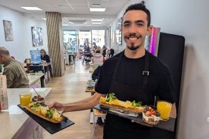 Uno de los camareros sirvinedo un desayuno de la Ruta '#unmardedesayunos'.