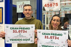 Los dueños de la administración mostrando los carteles del premio.