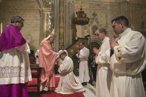 El obispo impone sus manos sobre los nuevos diáconos en la ceremonia.