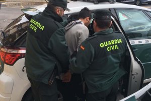 Agentes de la Guardia Civil introduce en un coche patrulla al mayor de los tres arrestados.