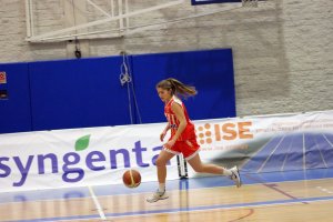 La jugadora rojilla camino de la canasta.