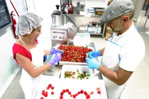 Isabel y biagio pelando fresas para mermelada en la fábrica que fue una carpintería.