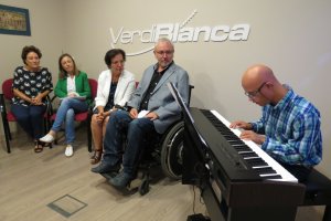 Antonio Sánchez de Amo con Gracia Fernández y Francisca Fernández escuchan a un músico con discapacidad.