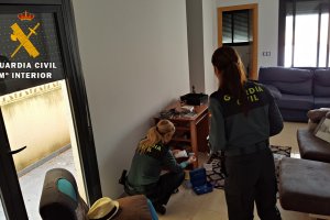 Dos agentes comprueban los efectos encontrados en la vivienda de los okupas