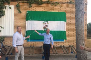 El delegado de Medioambiente y el alcalde izan la bandera.