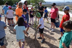Los pequeños plantan uno de los árboles ante la atenta mirada de sus madres.