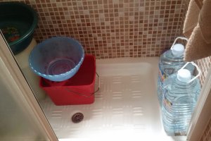 Plato de ducha preparado con garrafas y cubos de agua