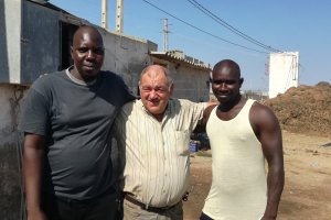 El pastor Antonio Cara se abraza a dos inquilinos de su vivienda: Mamadou y Ansumana.