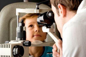 Un niño revisándose la vista en la consulta de un óptico-optometrista. L