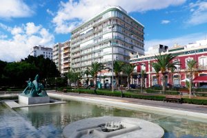 La fuente de los delfines precede a los bloques de pisos que miran hacia el puerto.