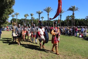 Soldados desfilando y recreando batallas y formaciones militares en el parque municipal acompañados en el otro extremo por diversos personajes de una
