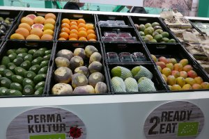 Stand con productos hortofrutícolas y una etiqueta de producción bajo técnicas de permacultura.