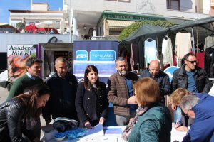 Un ciudadano firma la petición frente a los dirigentes del PP huercalense.