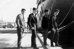 Cuatro amigos posando como los Beatles en una mañana de domingo en el puerto