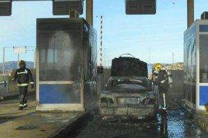 Bomberos junto al vehículo calcinado y las cabinas afectadas por el fuego.