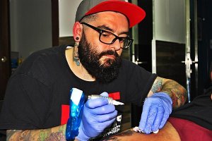 David Hernández Guerrero, Coco Guerrero en la profesión, tatúa el muslo de un cliente mientras va limpiando los rastros de sangre. 