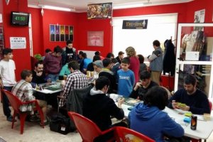 Varias personas, de todas las edades, reunidos  jugando a las cartas ‘Magic.’ 