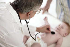 Un médico ausculta a un bebé en una consulta.