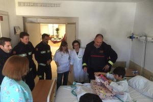 Un niño abre los regalos en presencia de algunos bomberos.