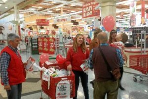 Un abuelo con su nieta conversa con dos voluntarios de Cruz Roja en Alcampo. 