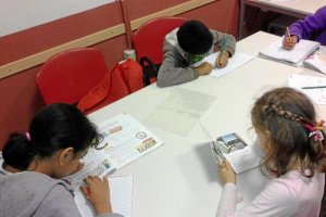 Niños del programa de apoyo escolar de Cruz Roja hacen la tarea en el aula de formación.