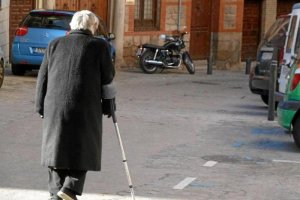 Una pensionista camina por una calle de un pueblo.