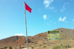 Bandera roja y panel informativo junto a la playa de Mónsul