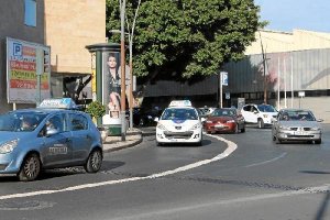 Dos coches de autoescuelas circulando por una concurrida calle de la capital.