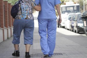 Una sanitaria asiste a una mujer en las cercanías de un centro de salud.