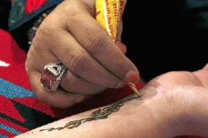 Un tatuador aplica henna natural sobre la piel.