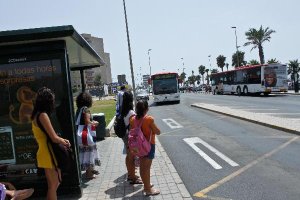Usuarios de Surbús esperan al autobús en una de las paradas junto a la playa.