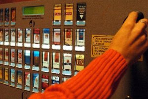 Una persona saca tabaco de una máquina expendedora.