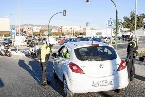 Efectivos de la Policía Local registran un vehículo en un control a la entrada del barrio. 