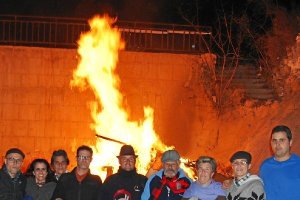 Un grupo de vecinos junto a una gran hoguera.