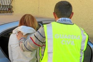 Un agente conduce a una de las detenidas al interior del vehículo policial.
