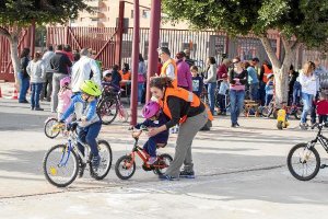 Un voluntario de Alpedal enseña a una niña a montar en bicicleta.