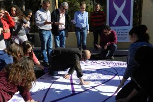Alcalde y jóvenes plasman sus manos en la pancarta.