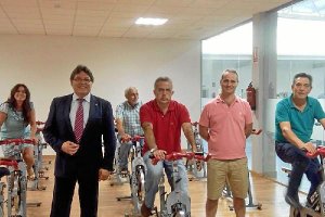 El alcalde, con traje, junto a concejales en las bicis estáticas.