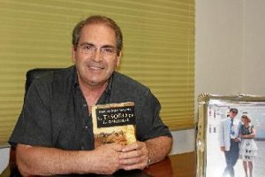 Manuel Ortiz sostiene un ejemplar de su libro junto a una fotografía familiar. 