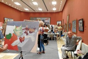 Antonio López, sentado en una silla y contemplando apacible cómo trabajaban en los lienzos sus avent