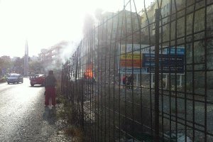 Imagen del coche ardiendo en el momento en el que los dos chicos (a la derecha) trasladan al conduct